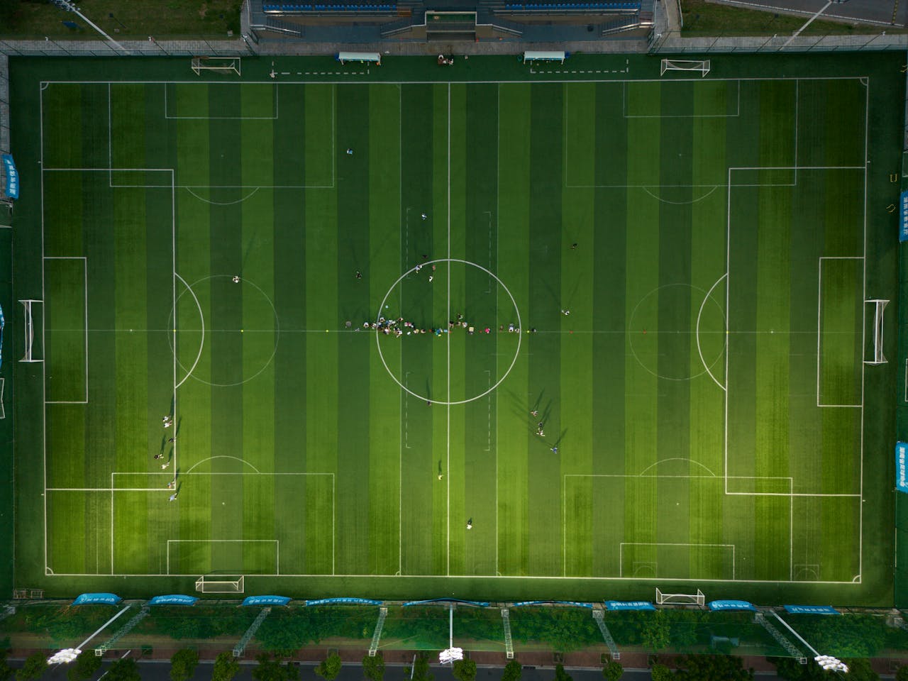 Top-down view of a soccer field with players during daytime.
